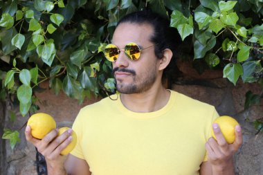 Açık havada limonlu sarı tişörtlü yakışıklı genç adamın portresi.