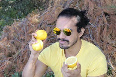 Açık havada limonlu sarı tişörtlü yakışıklı genç adamın portresi.