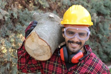 Kasklı yakışıklı oduncunun portresi omuzunda kütük tutuyor.