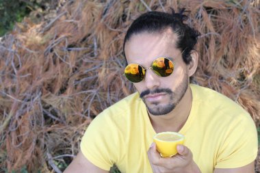 Açık havada limonlu sarı tişörtlü yakışıklı genç adamın portresi.