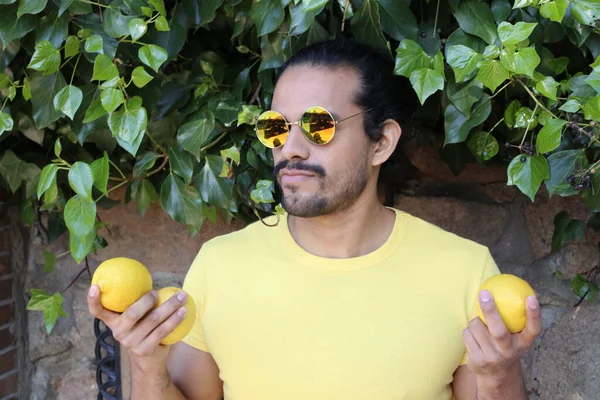 Açık havada limonlu sarı tişörtlü yakışıklı genç adamın portresi.