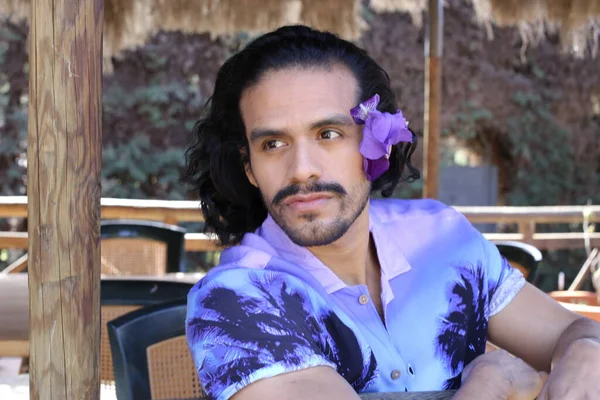 Açık havada orkide çiçekli, şık, mor gömlekli genç bir adamın portresi.