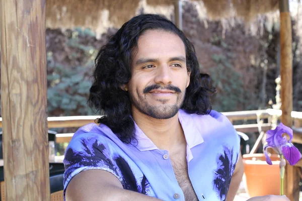 Açık havada orkide çiçekli, şık, mor gömlekli genç bir adamın portresi.