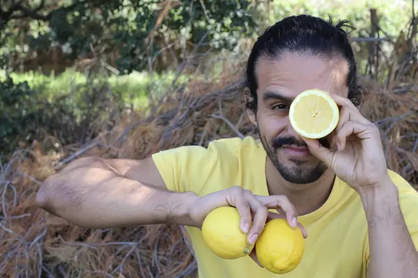 Açık havada limonlu sarı tişörtlü yakışıklı genç adamın portresi.