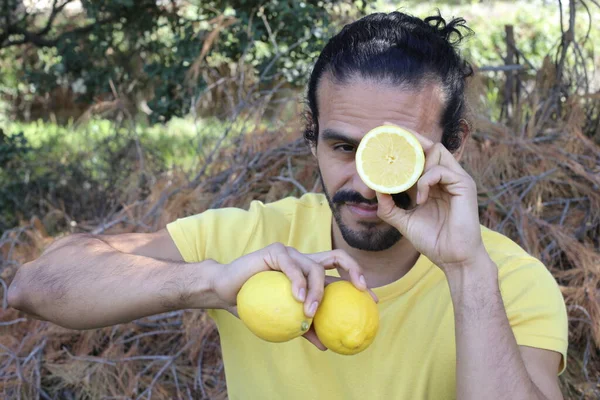 portrait of handsome young man in yellow t-shirt with lemons outdoors