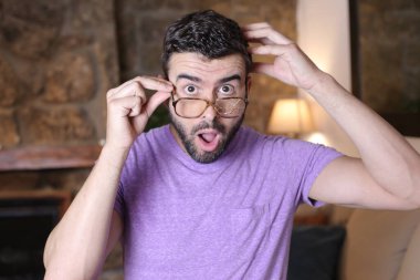 Evinde kırık gözlüklü yakışıklı bir gencin yakın plan portresi.