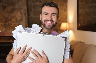 Evinde para dolu bir çanta taşıyan yakışıklı bir gencin yakın plan portresi.