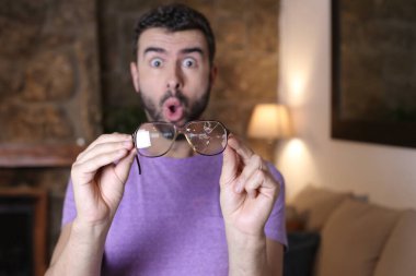 Evinde kırık gözlüklü yakışıklı bir gencin yakın plan portresi.