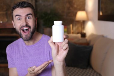 Evdeki haplar için boş kutu tutan yakışıklı genç adamın yakın plan portresi.