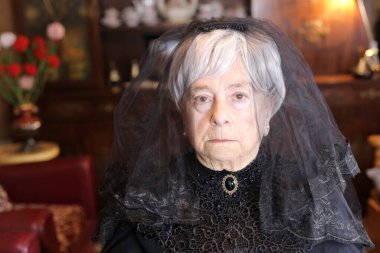 Siyah elbiseli olgun bir kadının yakın plan portresi.