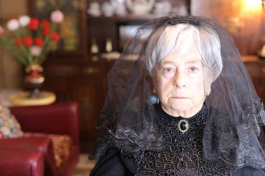 Siyah elbiseli olgun bir kadının yakın plan portresi.