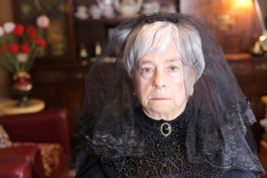 Siyah elbiseli olgun bir kadının yakın plan portresi.