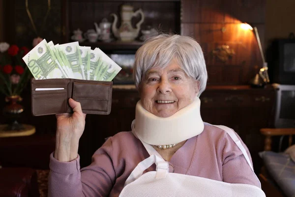 close-up portrait of mature injured woman holding wallet full of cash at home