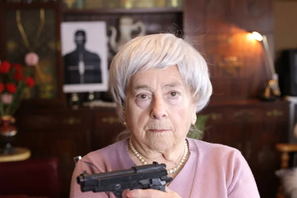 自宅に拳銃を持った熟女のクローズアップ肖像画 — ストック写真