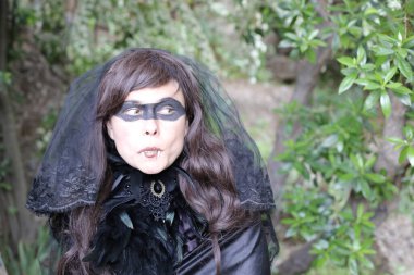 Siyah elbiseli genç bir kadının portresi. Parkta gözlerinde boya var.