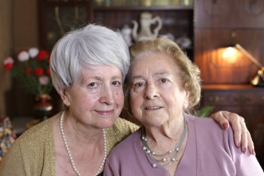 Evde birlikte vakit geçiren iki olgun kadının portresi.