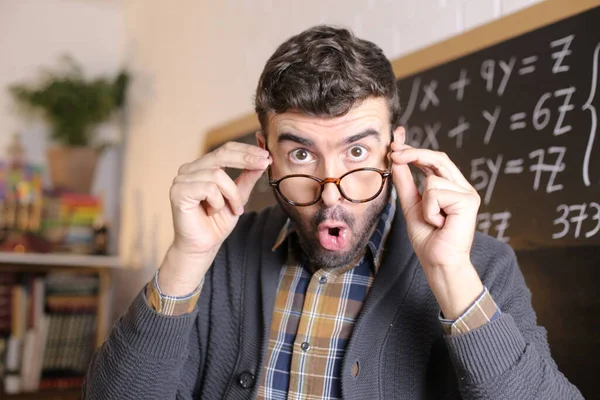 感情用事的年轻教师的特写 带着眼镜出现在教室黑板前 — 图库照片