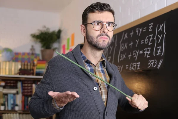 close-up portrait of angry young teacher in front of blackboard in classroom