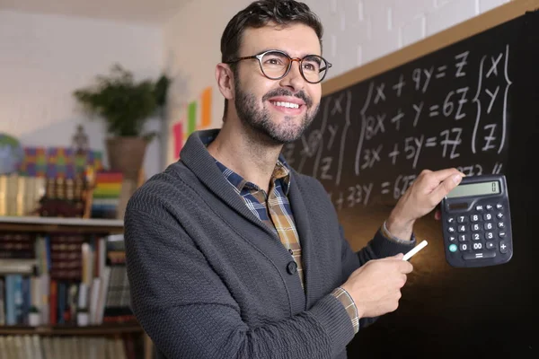 Close Portrait Handsome Young Teacher Holding Chalk Calculator Front Blackboard — Zdjęcie stockowe