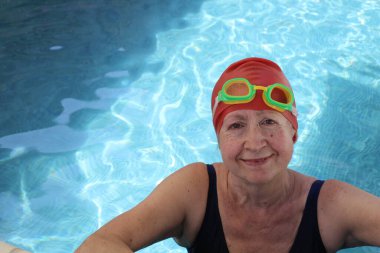 Güneşli yaz gününde bilardoda yüzme şapkalı ve gözlüklü olgun kadın portresi.