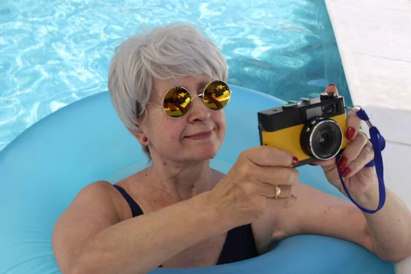 日当たりの良い夏の日にプールでヴィンテージフィルムカメラを保持水着で成熟した女性の肖像画 — ストック写真