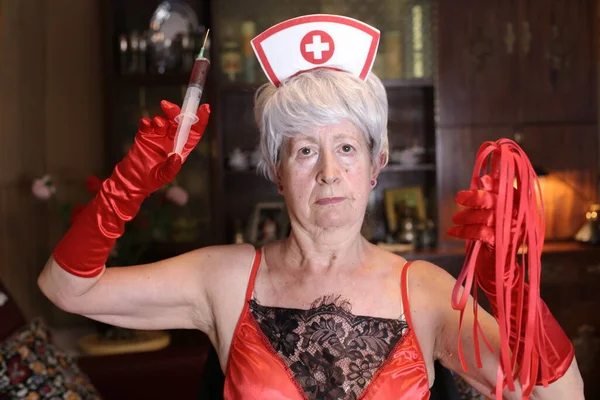 穿着护士丝质服装的成熟女人在家里带注射器的特写镜头 万圣节庆祝概念 — 图库照片