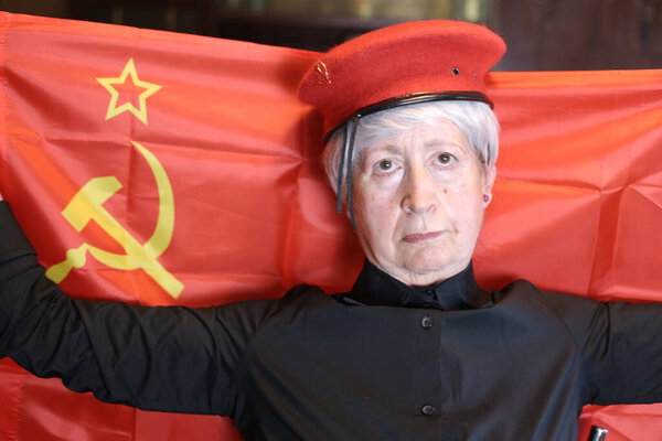 close-up portrait of mature woman in soldier costume with ussr flag at home, Halloween celebration concept