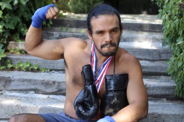 Yakışıklı, karma ırk sporcusunun, boks eldivenli ve açık havada altın madalyalı portresi.