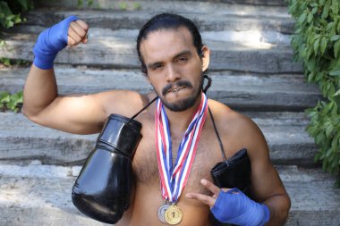 Yakışıklı, karma ırk sporcusunun, boks eldivenli ve açık havada altın madalyalı portresi.