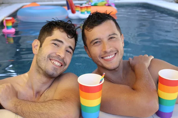 幸せな若いゲイのカップル一緒にプールで彼らの時間を楽しんで紙コップでLgbtqフラグの色 — ストック写真