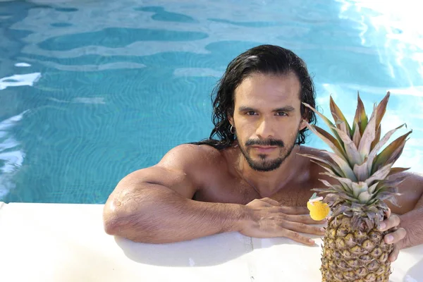 年轻帅气的混血男子与菠萝在游泳池里的特写镜头 — 图库照片