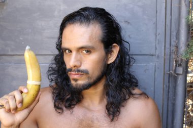 Yakından çekilmiş, genç, yakışıklı, melez, tişörtsüz, prezervatifli bir adamın portresi.