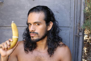 Yakından çekilmiş, genç, yakışıklı, melez, tişörtsüz, prezervatifli bir adamın portresi.