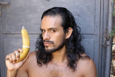 Yakından çekilmiş, genç, yakışıklı, melez, tişörtsüz, prezervatifli bir adamın portresi.