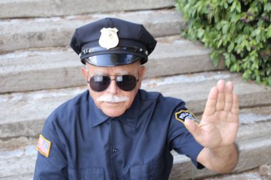 Polis kostümü giymiş yakışıklı son sınıf öğrencisinin açık hava hareketini gösteren yakın plan portresi.