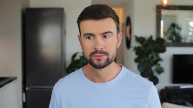 Sakallı, sıradan giyinmiş, kameraya bakan genç adama yaklaş.