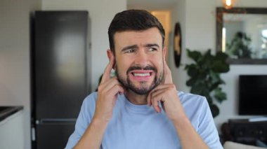 Evde kulaklarını kapatan sinirli bir adam.