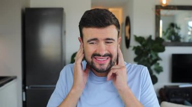 Evde kulaklarını kapatan sinirli bir adam.