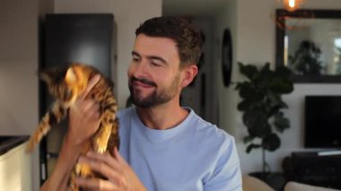 Bengal kedisi tutan yakışıklı adamın portresi.