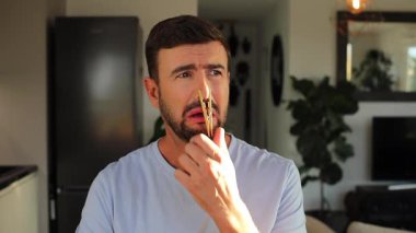 Mandallı adam burun deliklerini tıkıyor.