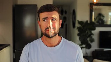 Mandallı adam burun deliklerini tıkıyor.