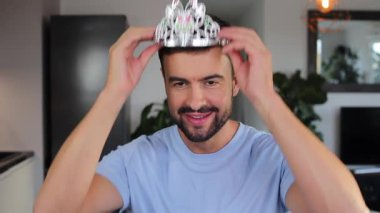 Gümüş taç takan ve gülümseyen bir adam..