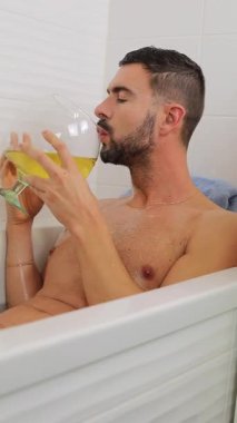 Yakışıklı adam küvette dinlenirken içkinin tadını çıkarıyor..