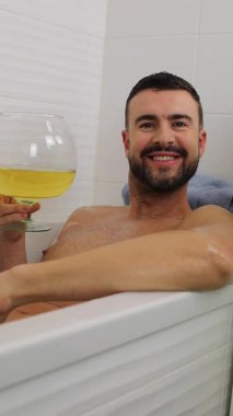 Yakışıklı adam küvette dinlenirken içkinin tadını çıkarıyor..