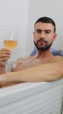 Adam küvette dinlenirken içkinin tadını çıkarıyor..