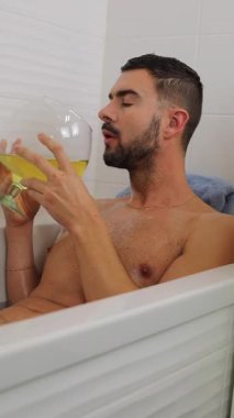 Adam küvette dinlenirken içkinin tadını çıkarıyor..