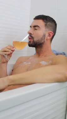 Adam küvette dinlenirken içkinin tadını çıkarıyor..