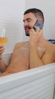 Genç adam telefonda konuşurken küvette dinleniyor..