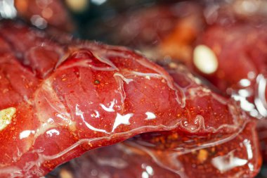 Parlak, sulu salamura edilmiş baharatlı et dilimleri, yağ ve susam tohumları. Kurutulmuş et, makro resim..  