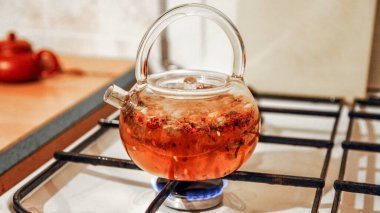 Kırmızı çay içeceği, gaz ocağında cam bir çaydanlıkta kaynatılır, yakın çekim görüntüsü..